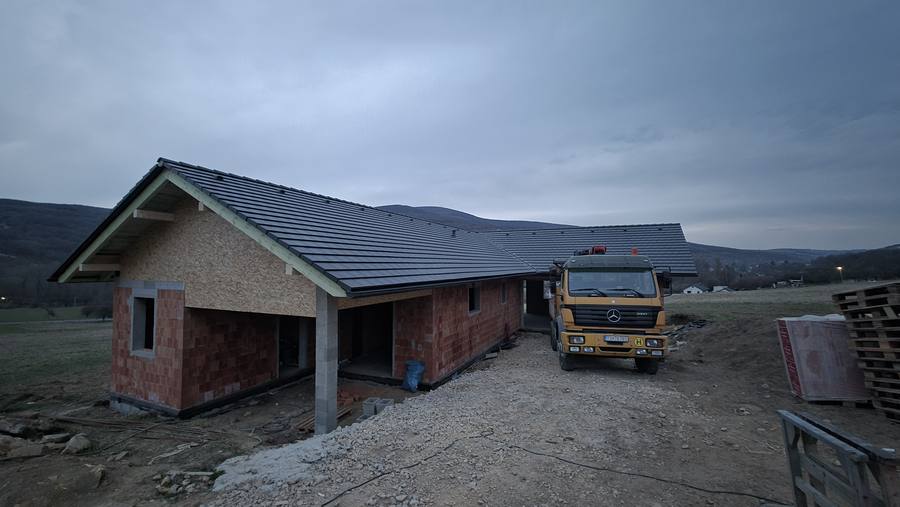 Dokončená strecha s tmavou krytinou na novostavbe bungalovu