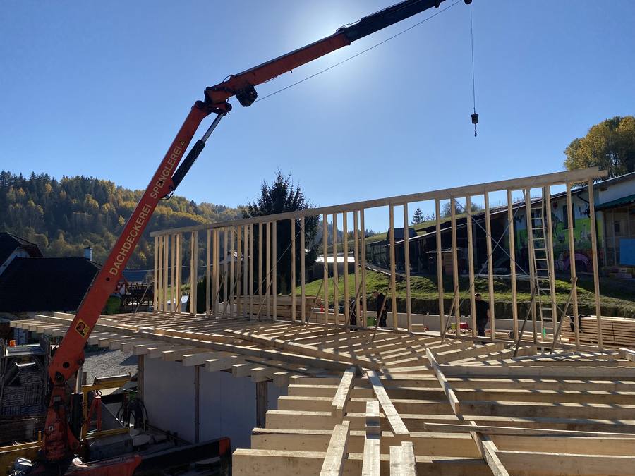 Montáž dlhej drevenej konštrukcie so žeriavom na stavbe
